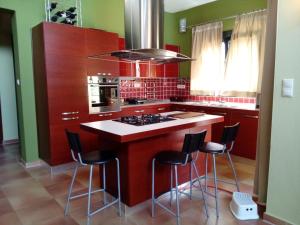 a kitchen with red cabinets and a island with bar stools at Vicente House in Skala Rachoniou