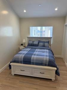 Un dormitorio con una cama con edredón azul y una ventana. en cozy & Elegant Torrance Apartment with balcony, en Torrance