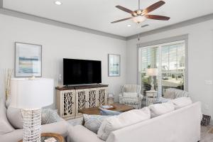 a living room with white furniture and a flat screen tv at Endless Summer in Gulf Shores