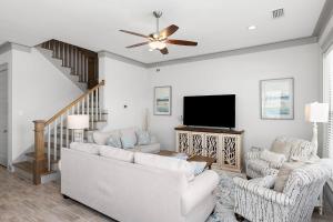 a living room with white furniture and a flat screen tv at Endless Summer in Gulf Shores
