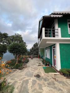 a green and white building with a balcony and flowers at Dara Homestay, Charkhole in Kalimpong