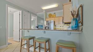 a kitchen with two bar stools and a counter at Island Royale P202 in Gulf Shores +13 photos