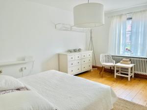 ein weißes Schlafzimmer mit einem weißen Bett und einem Stuhl in der Unterkunft Wohnung Bel Etage im historischen Amtshaus in Fehmarn