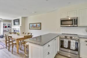 a kitchen with white cabinets and a table and a dining room at Lodge Condo 35 in Stowe