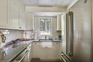 a kitchen with white cabinets and a stainless steel refrigerator at Lodge Condo 35 in Stowe