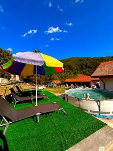a pool with chairs and an umbrella next to a swimming pool at Casa Mihai in Bîsca Rozilei