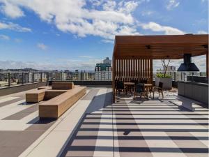 una terraza en la azotea con bancos y mesas en un edificio en JP Redenção by My Way, en Porto Alegre