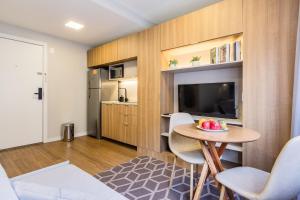 Una sala de estar con una mesa y sillas y un televisor. en JP Redenção by My Way, en Porto Alegre