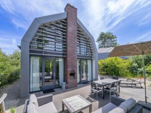 an outdoor patio with tables and chairs and a building at Beautiful holiday home with terrace in Egmond aan den Hoef