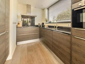 a kitchen with wooden cabinets and a large window at Beautiful holiday home with terrace in Egmond aan den Hoef