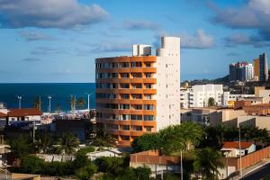 a tall white building with the ocean in the background at Flat beira-mar Natal in Natal