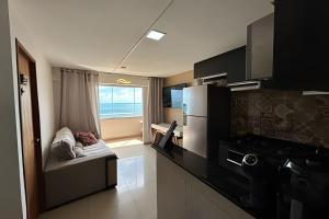 a small kitchen with a couch and a refrigerator at Flat praia a beira-mar in Natal