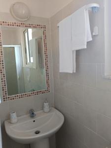 ein weißes Badezimmer mit Waschbecken und Spiegel in der Unterkunft Una Finestra sul mare in Villa San Giovanni