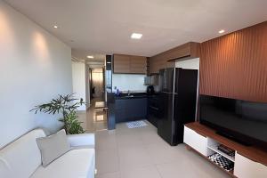a living room with a television and a kitchen at Flat à beira-mar com vista para a praia do meio in Natal