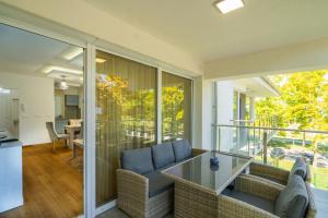 a living room with a glass table and chairs on a balcony at Sunshine Resort Blue Apartman in Zamárdi