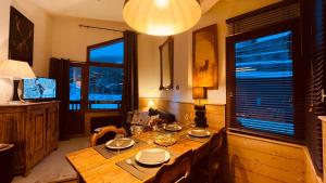 una sala da pranzo con tavolo in legno e 2 finestre di Appartement Le Cerf- T2 sur front de neige - LA TANIA a Courchevel