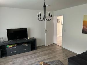 a living room with a flat screen tv and a chandelier at Ferienwohnung Appartement am Wildpark Bad Harzburg in Bad Harzburg