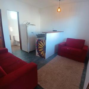 Una sala de estar con dos sofás rojos y una cocina. en Pousada Adam, en Porto Seguro