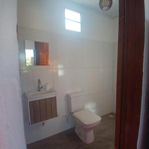 Un baño con inodoro, lavabo y ventana. en Pousada Adam, en Porto Seguro