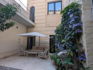 a patio with chairs and an umbrella and flowers at Cosy home in Three Cities in Taʼ Penza +4 photos