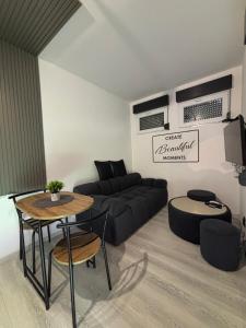 een woonkamer met een zwarte bank en een tafel bij Wood & Chill House in Sarajevo