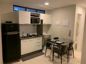 a kitchen with a black refrigerator and a table with chairs at Flats Mobiliados Zona Norte, Casa Forte e Recife in Recife
