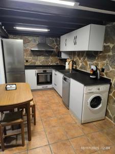 a kitchen with white cabinets and a table and a washer at La Casa de la Miel in Ramales de la Victoria