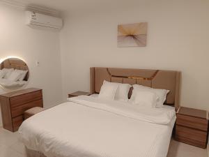 a bedroom with a large bed with white sheets at Al Qurashi Residences Al Nakhil Dammam in Dammam