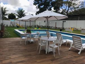 two tables and chairs with umbrellas next to a pool at Flats Mobiliados Zona Norte, Casa Forte e Recife in Recife