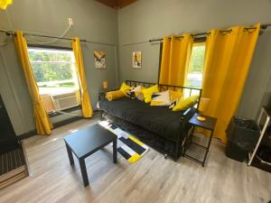 a living room with a black bed with yellow pillows at Motel Magistral in St-Raphael-de-Bellechasse