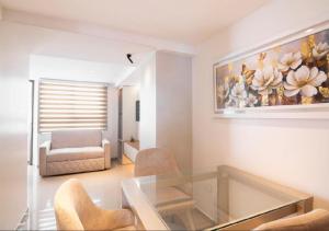 a living room with a glass table and a painting on the wall at Trento Class 1001 Elegante y Confortable con Parqueadero in Bucaramanga