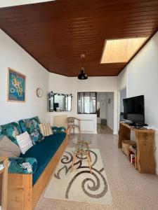 een woonkamer met een blauwe bank en een tv bij Départ du Marin à la Cotinière in Saint-Pierre-dʼOléron