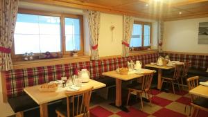 a restaurant with three tables and chairs and windows at Haus Zeinissee in Galtür