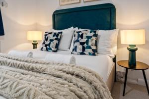 a bedroom with a bed with a green headboard and two lamps at City Nest Service Accommodation HEATHROW Beautiful Spacious Home 5 min drive to Heathrow Airport Great transport links to Central London FREE PARKING! in West Drayton