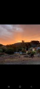 un tramonto in un campo con il tramonto di Recanto das palmeiras 2 a São Thomé das Letras Altre 10 foto