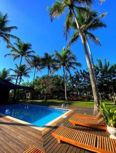 una piscina con 2 bancos y palmeras en Studio 64 - Trancoso, en Porto Seguro