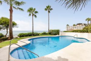 a swimming pool with palm trees and the ocean at The loving hummingbird in Mijas Costa