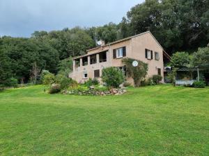 a large house on a grassy field with trees at Chambre avec salle de bain in Penta-di-Casinca