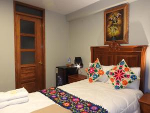 a bedroom with a bed with colorful pillows on it at Rumi Wasi Inn Ollantaytambo in Ollantaytambo