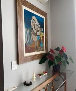 a painting of a woman on a wall next to a table at Casa Dani · CURTA! |143| Aconchegante Casa 3 suíte in Joinville