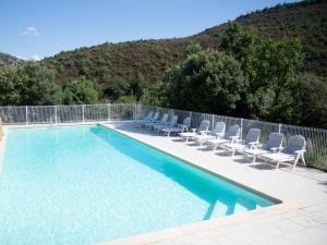 a swimming pool with lounge chairs next to a fence at Oleandre in Cassagnolles