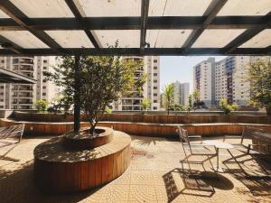 un patio avec un arbre et des chaises sur un bâtiment dans l'établissement Santorini 2507-Bueno, à Goiânia