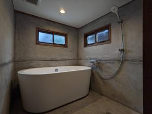 un baño con bañera y ducha en コワーキングスペース kuzume Base ゲストハウス 古朴-MOKU-1棟貸の宿, en Konan