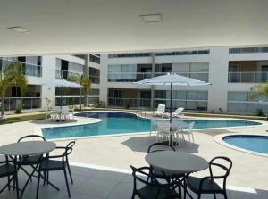 a pool with tables and chairs next to a building at varandasdofrancesapt216 Praia do Frances in Praia do Frances