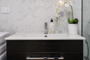 a bathroom with a white sink and a black cabinet at Stylish City Apartment with Balcony and Parking in Christchurch +17 photos
