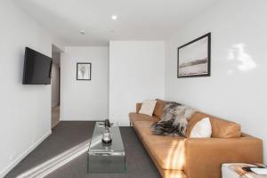 a living room with a couch and a table at Stylish City Apartment with Balcony and Parking in Christchurch