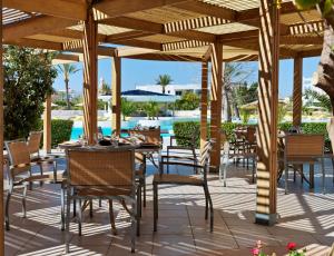 un patio con tavoli, sedie e piscina di Vincci Saphir Palace & Spa a Hammamet