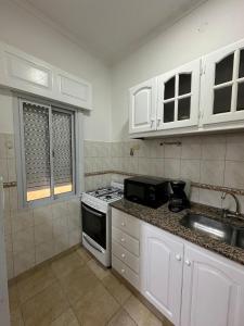 a kitchen with white cabinets and a stove top oven at Departamento en Microcentro in Resistencia