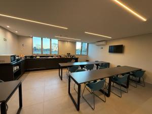 a large room with tables and chairs and a kitchen at Hotel Salute Brasília l SLEEP HOTÉIS in Taguatinga
