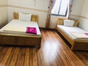 two beds in a room with wooden floors at Thanh Binh Hotel in Hà Tĩnh